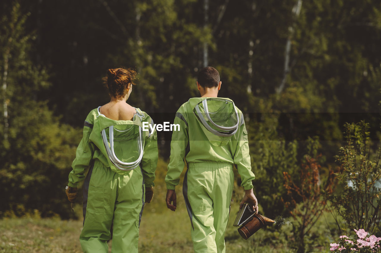 Beekeepers wearing protective suits walking together at apiary