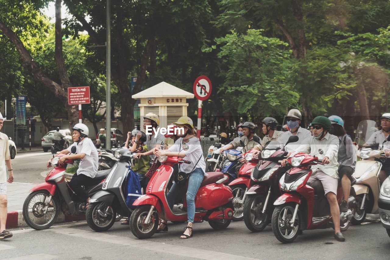 PEOPLE ON ROAD BY TREES ON STREET