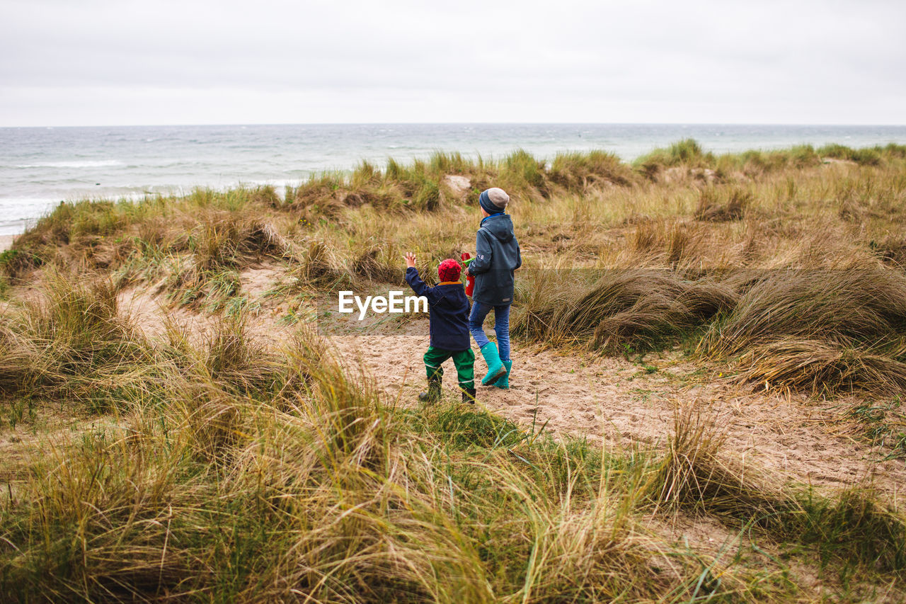 Full length of two boys walking through baltic grassland 