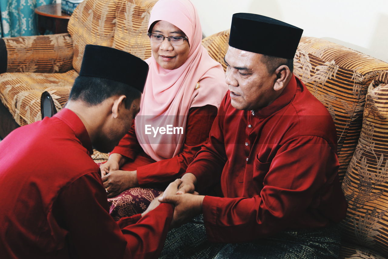 High angle view of siblings wearing traditional clothing while shaking hands at home