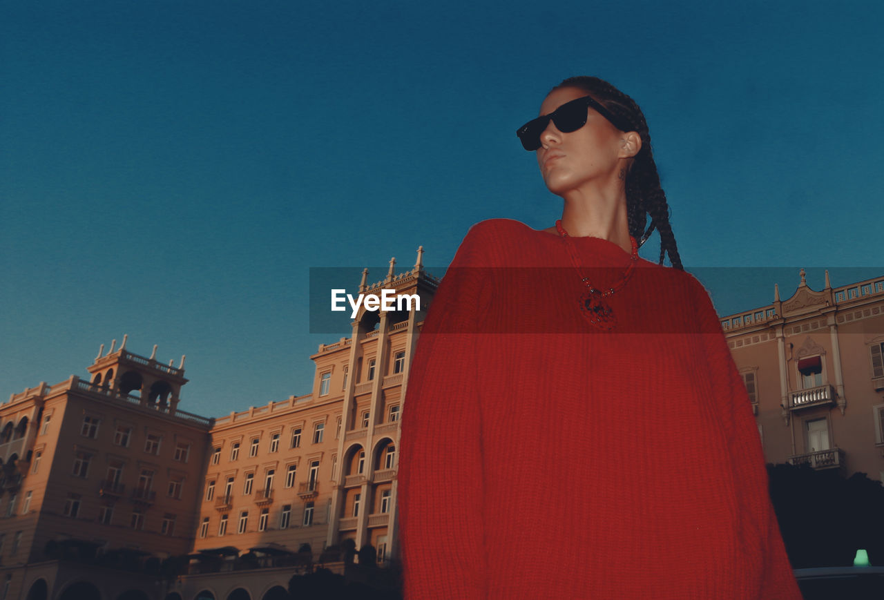 Portrait of woman wearing sunglasses standing against clear sky