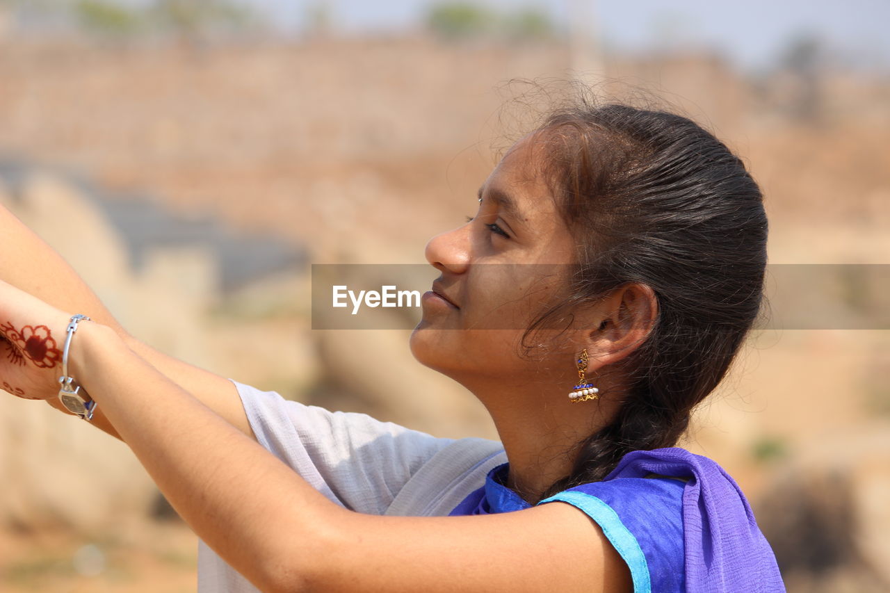 Side view of teenage girl looking away while standing outdoors