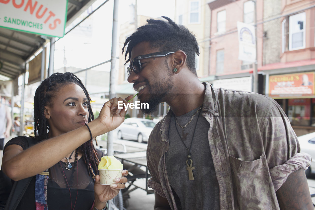 A young woman feeiding a young man frozen yogurt.