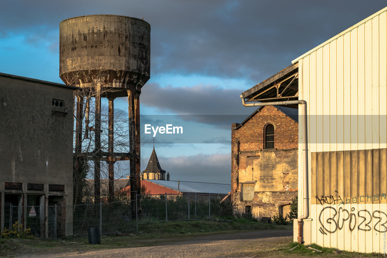 Water tower and houses against cloudy sky