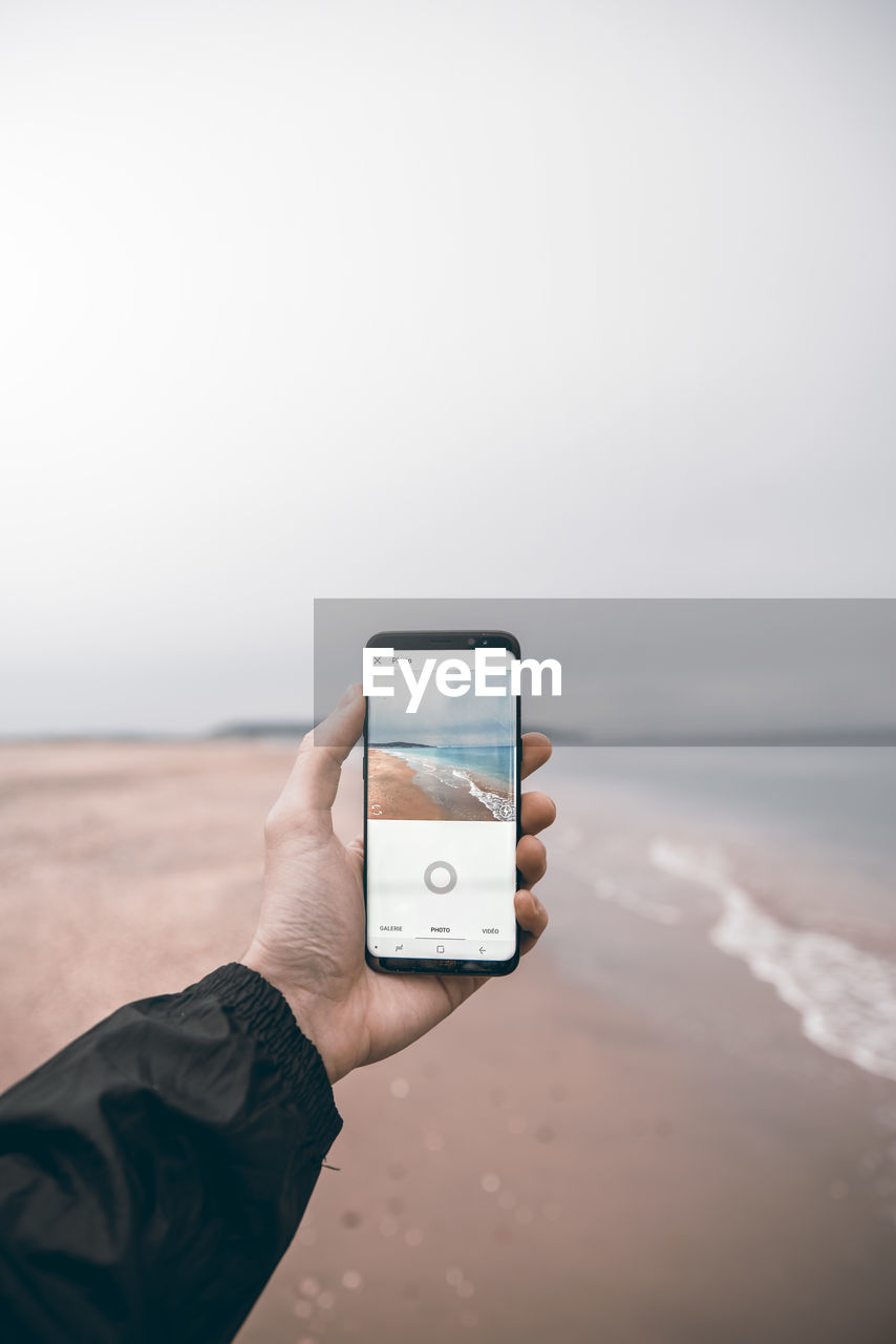 MAN PHOTOGRAPHING WITH MOBILE PHONE IN SEA