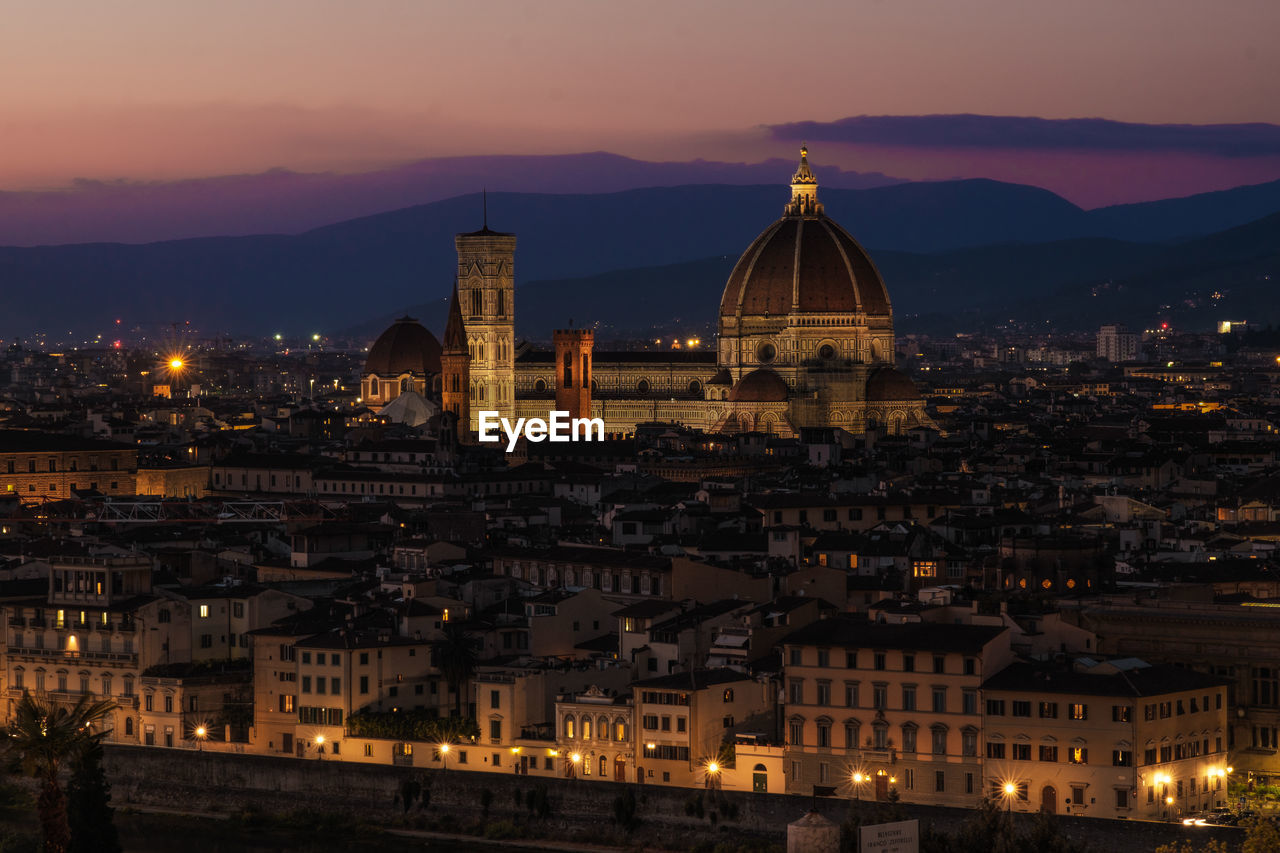 High angle view of illuminated buildings in city at sunset