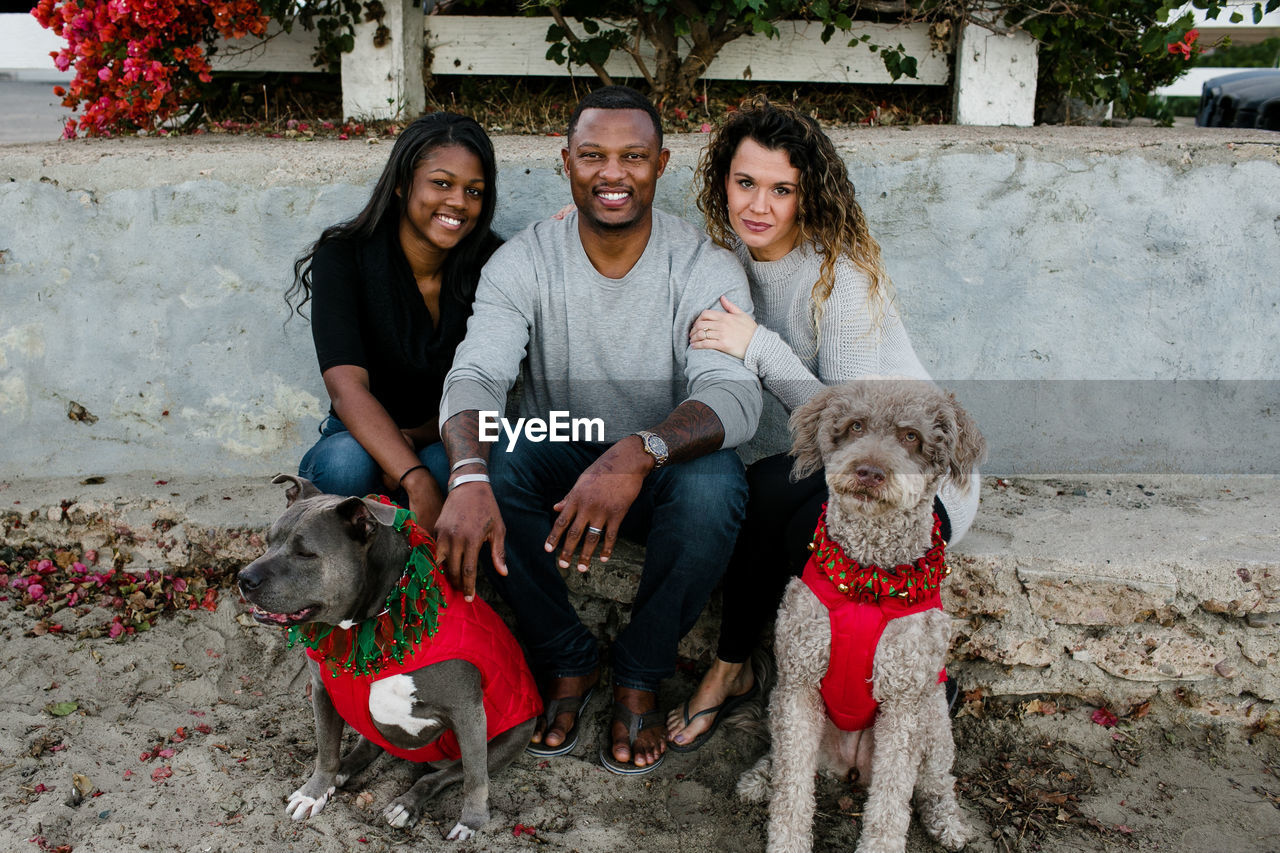 Blended family with dogs smiles at camera on beach at sunset