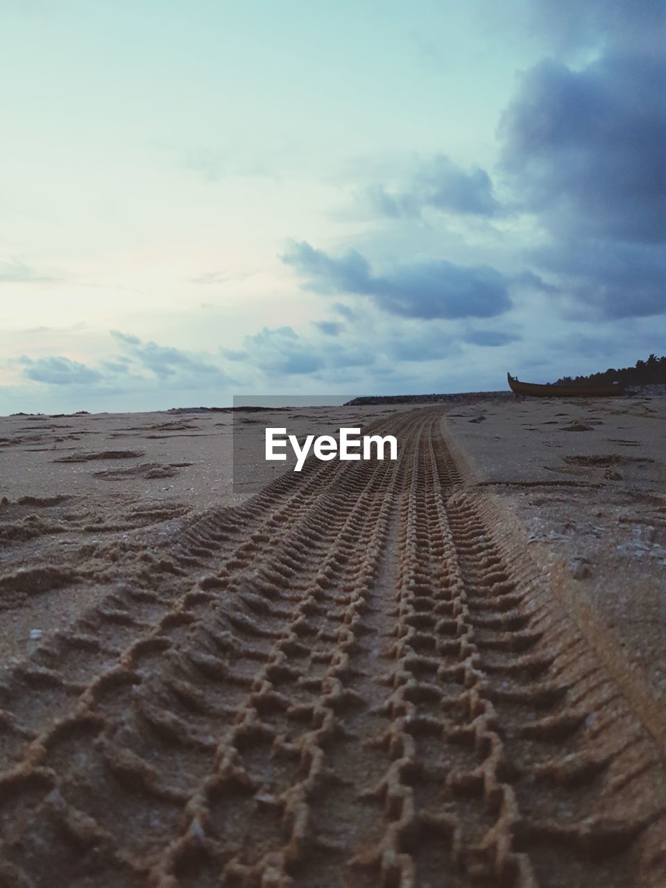 Tire tracks on sand dune against sky