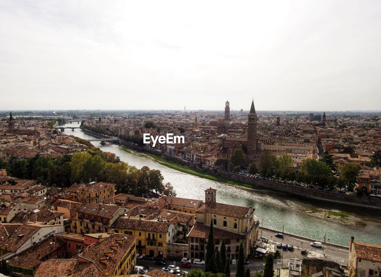 HIGH ANGLE VIEW OF BUILDINGS AND RIVER AGAINST SKY