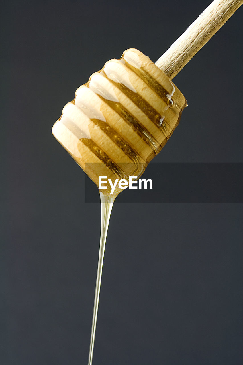 Close-up of honey dipper against black background