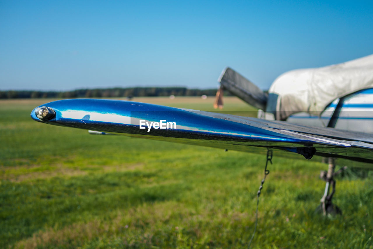 Close-up of airplane on field against sky