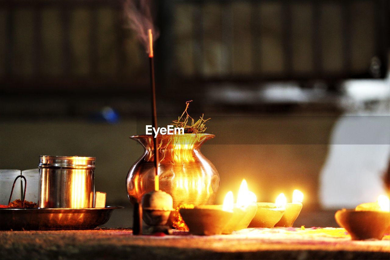 Close-up of illuminated diyas on table