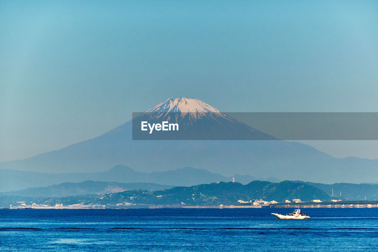 Scenic view of sea and snowcapped mountain against clear sky in the morning