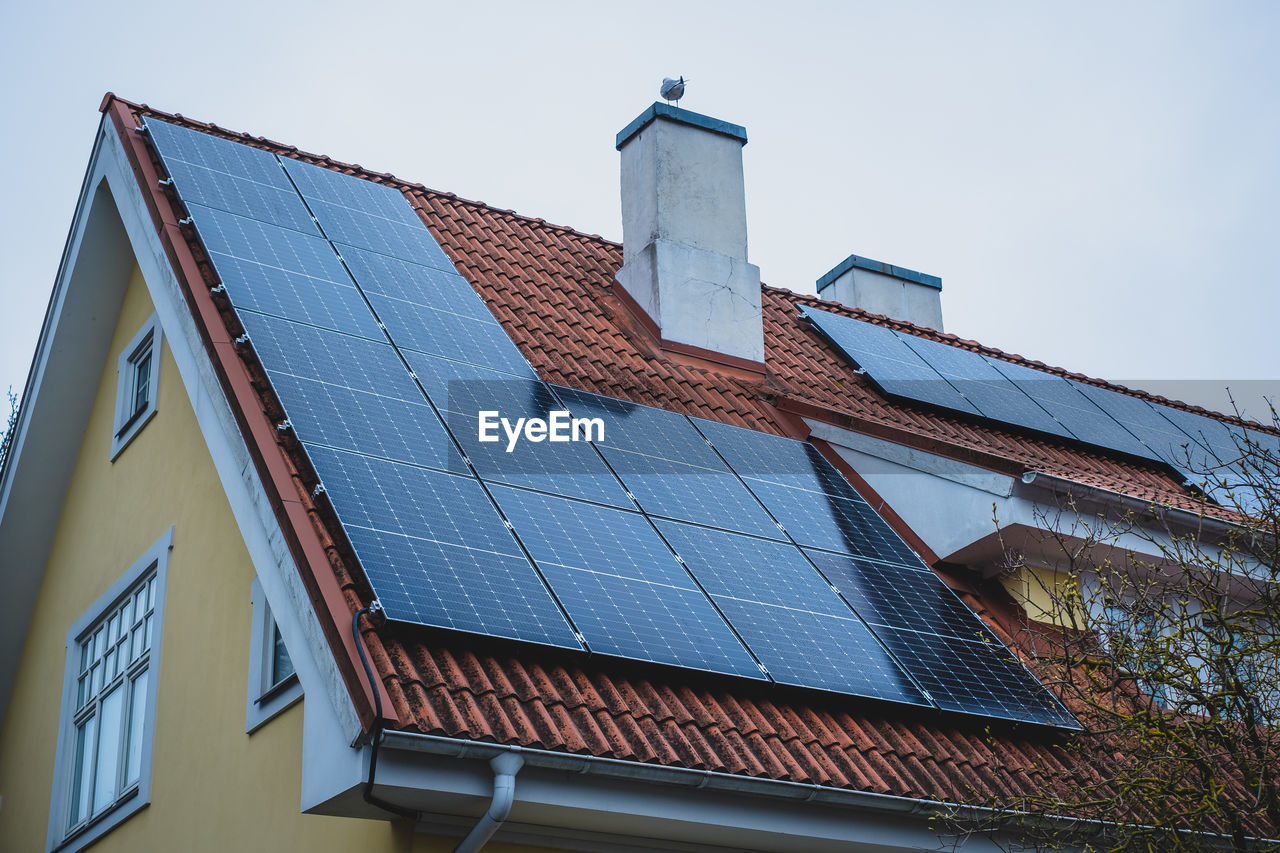 Close-up of solar panels installed on historic building gable roof with chimney.