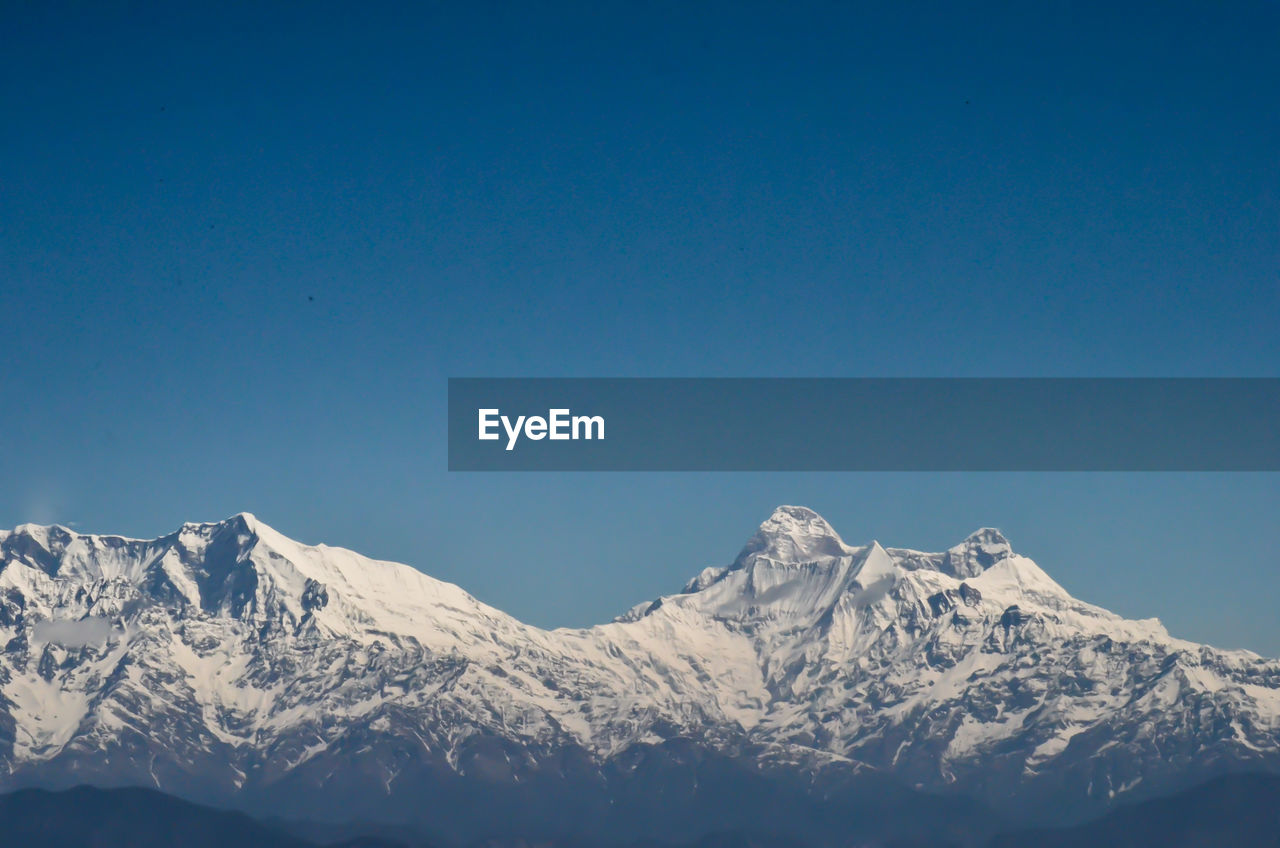 Scenic view of snowcapped mountains against clear blue sky