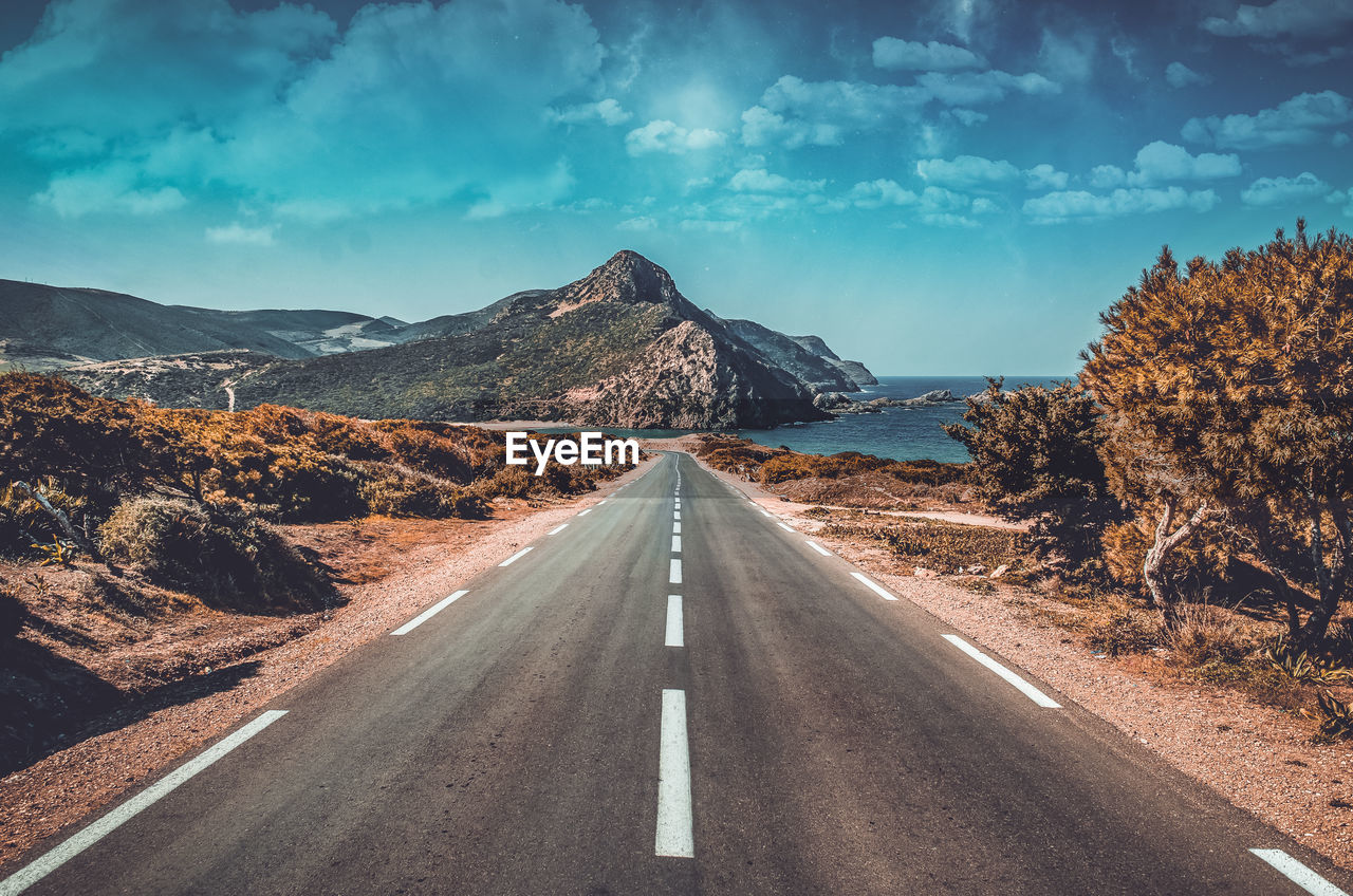 Road by mountains against sky