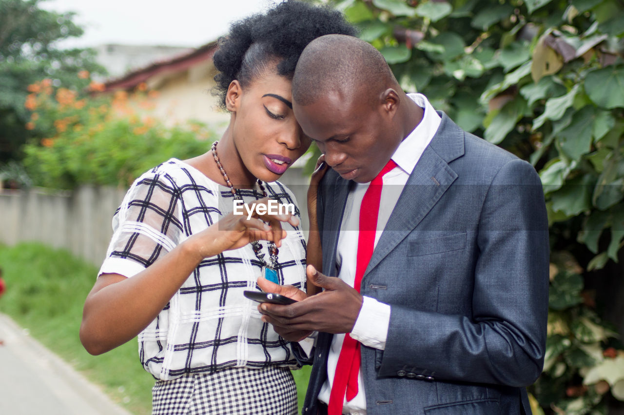 Business people consulting a mobile phone on the street, to see a money transfer