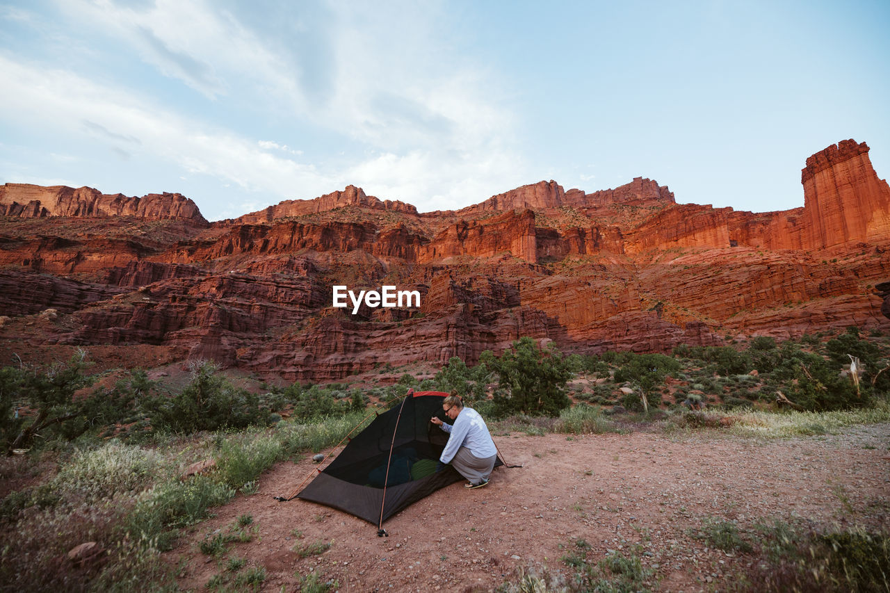 Woman sets up her tent under the orange red glow of fisher towers moab