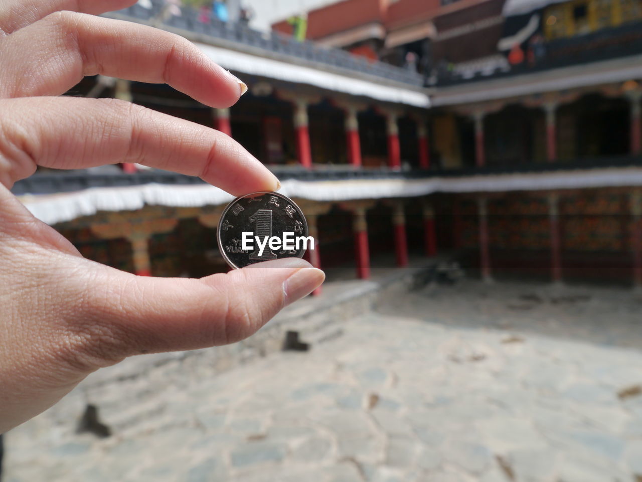 Cropped image of hand holding coin in buddhist temple