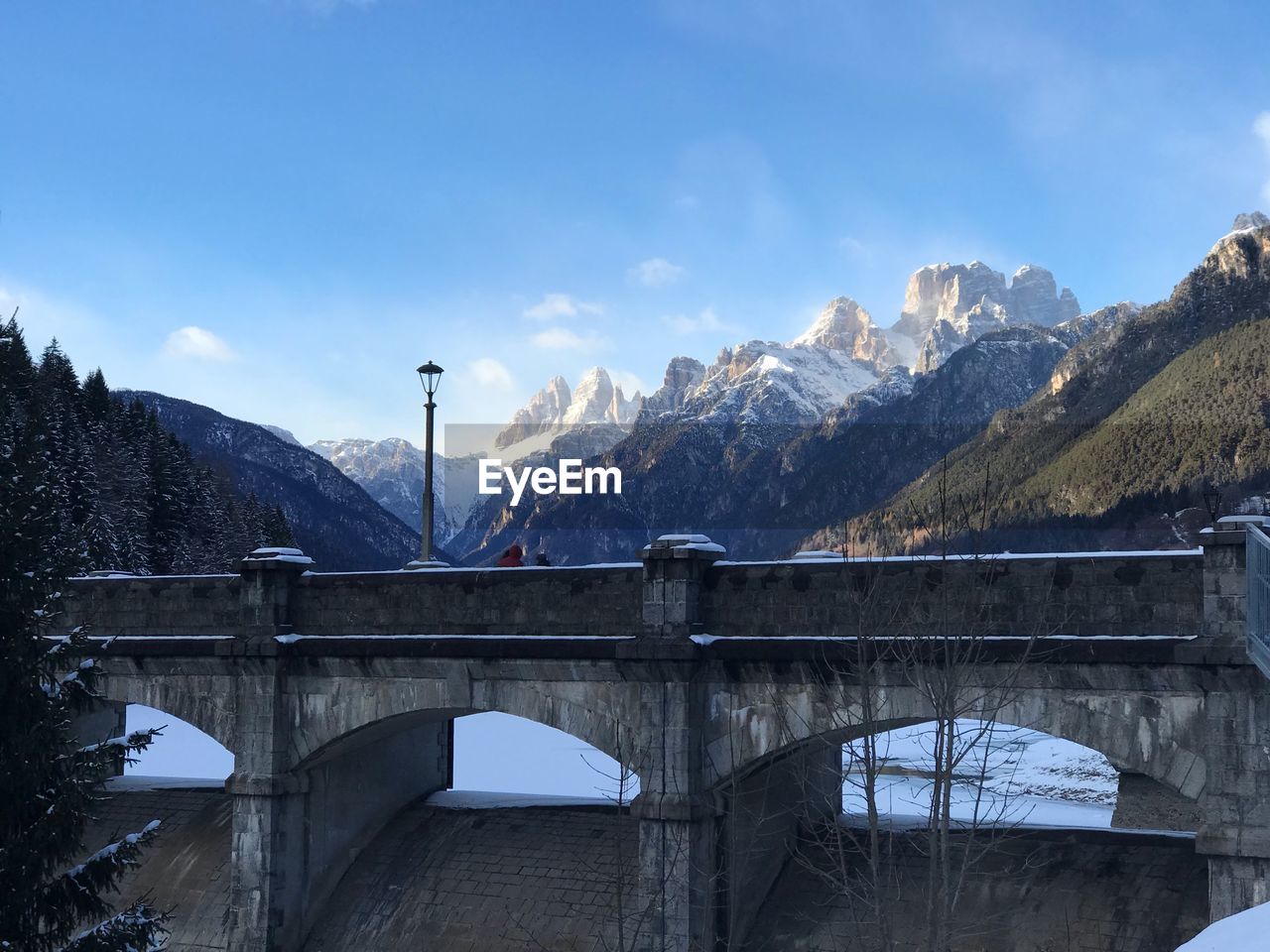 Arch bridge over snowcapped mountains against sky