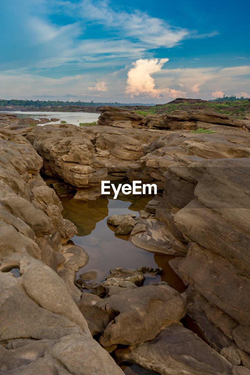 ROCK FORMATIONS ON SHORE AGAINST SKY