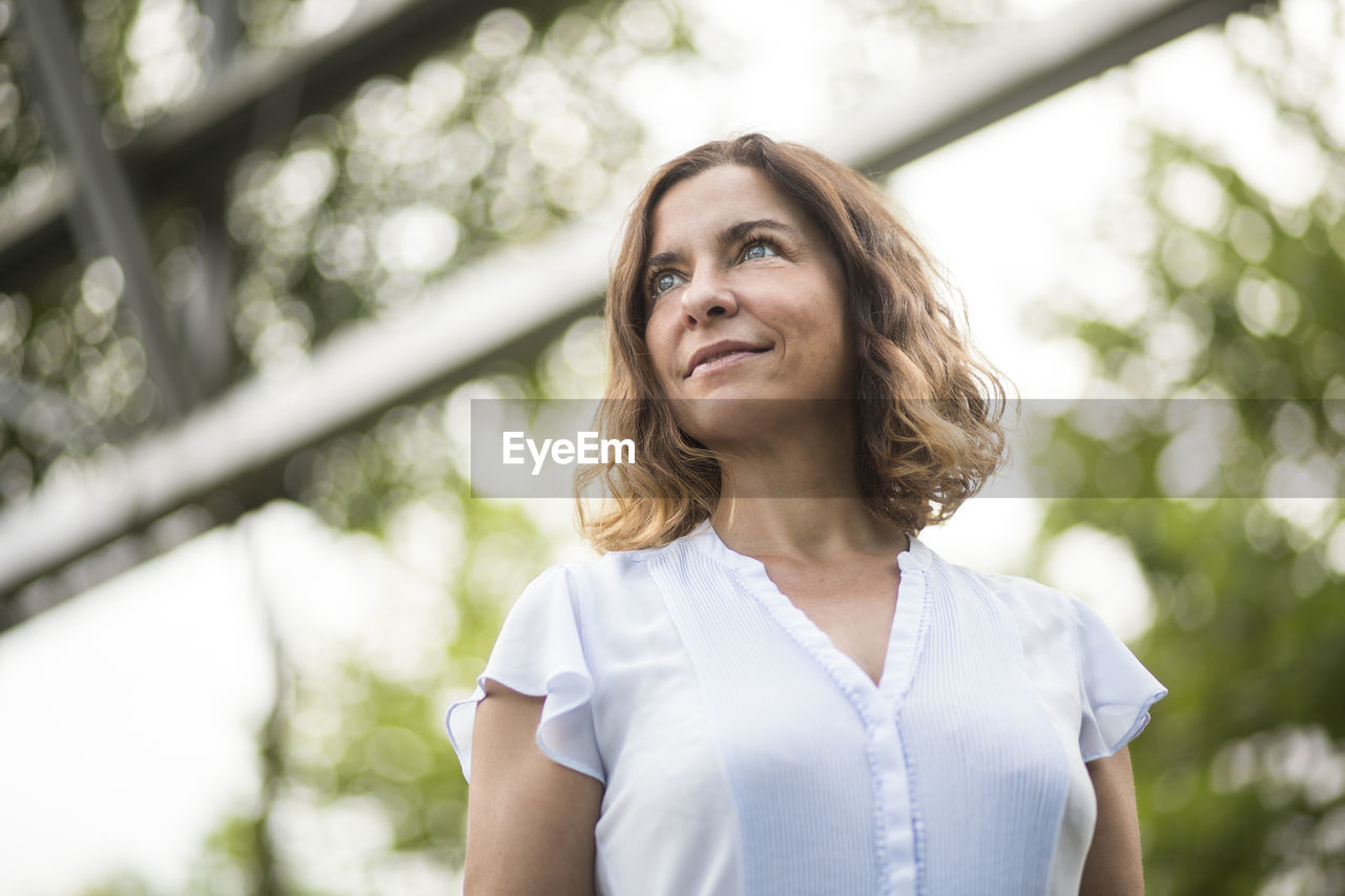 LOW ANGLE PORTRAIT OF WOMAN AGAINST SKY