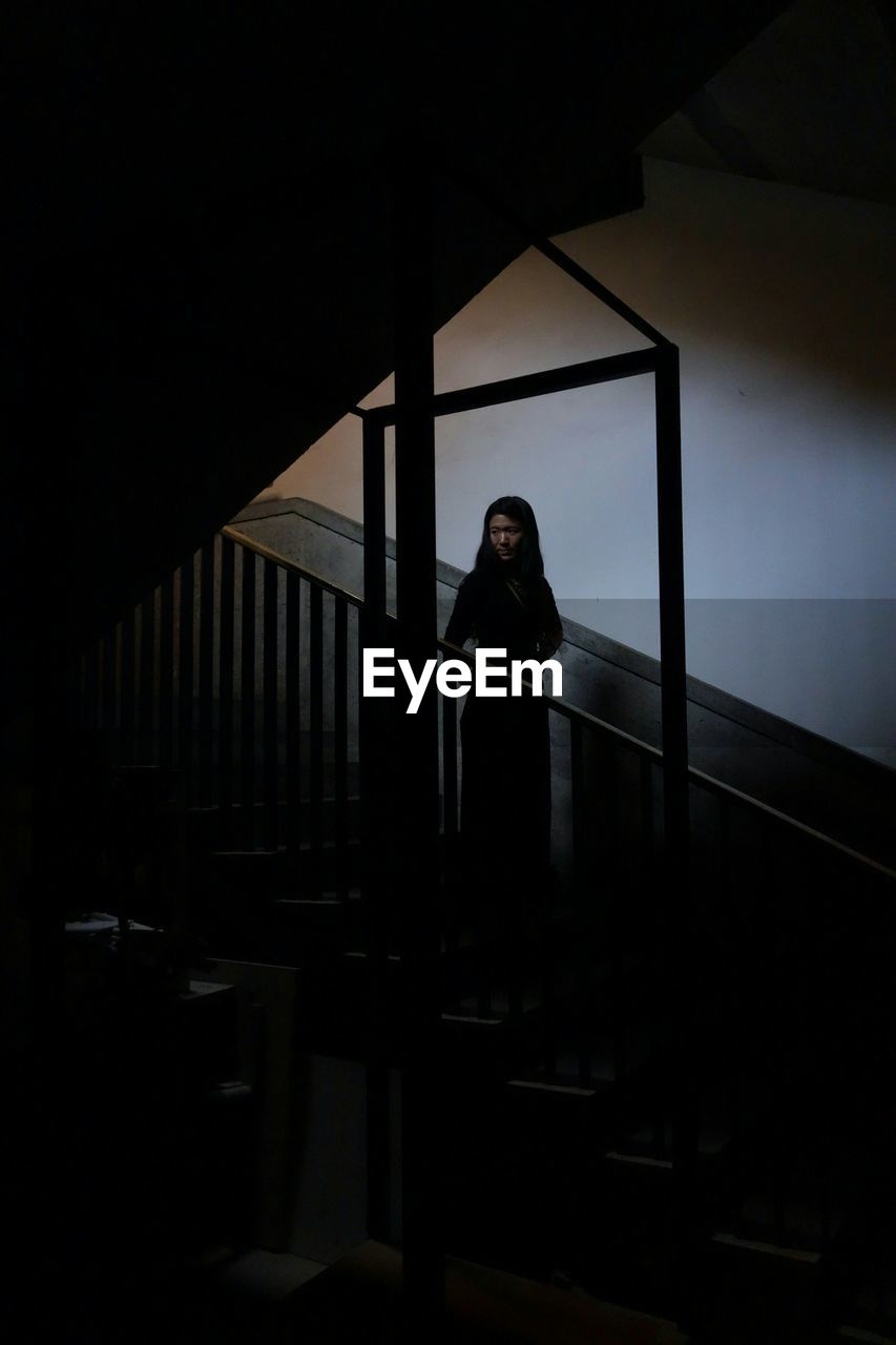 YOUNG WOMAN STANDING IN THE DARK