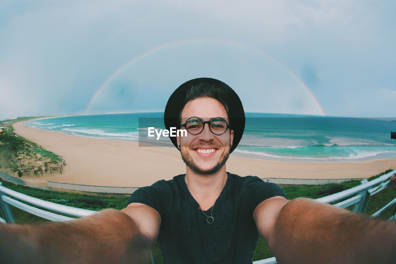 Portrait of smiling man taking selfie at the beach