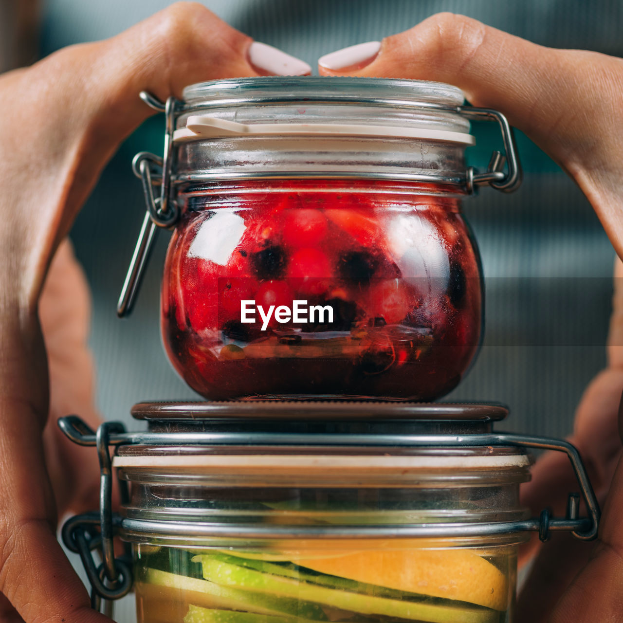 Woman holding jars with fermented fruits.