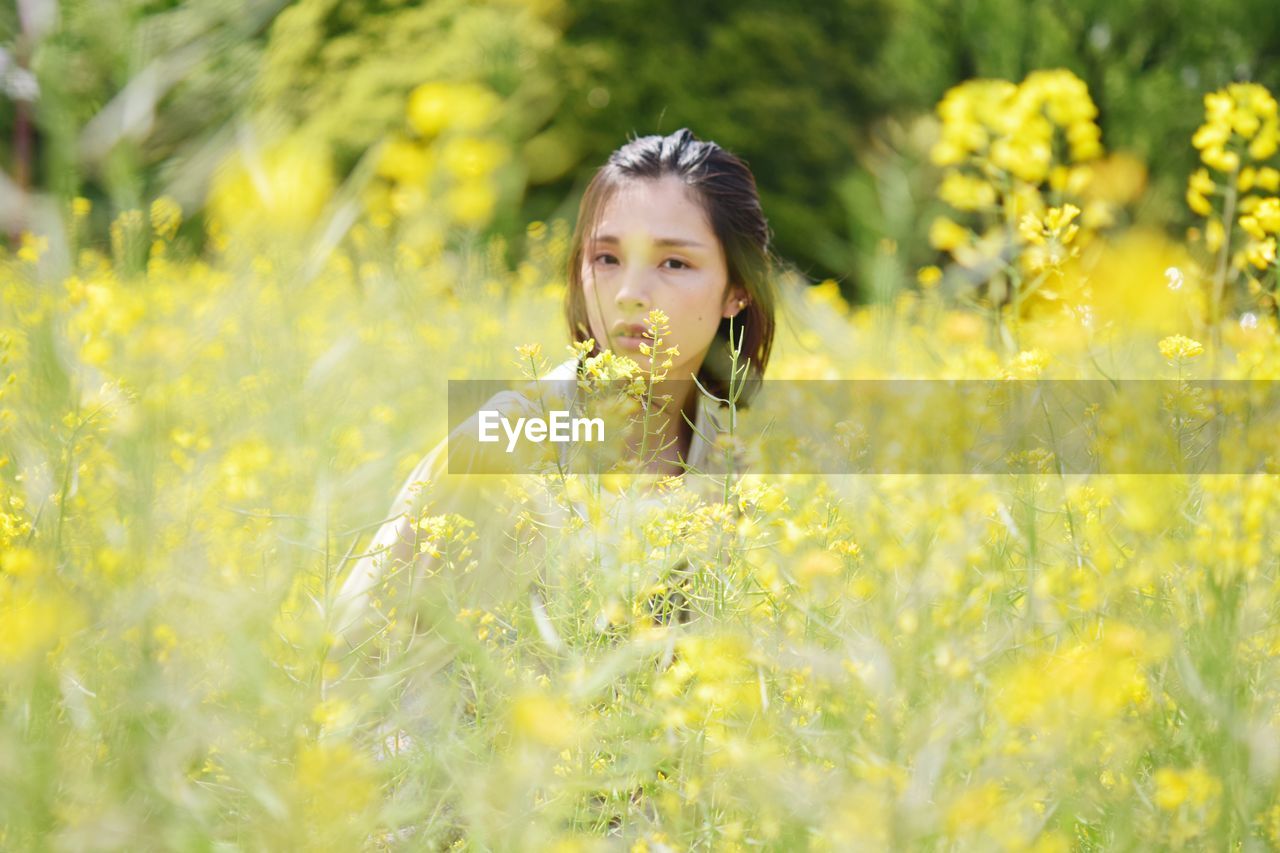 Portrait of woman with yellow flowers on field