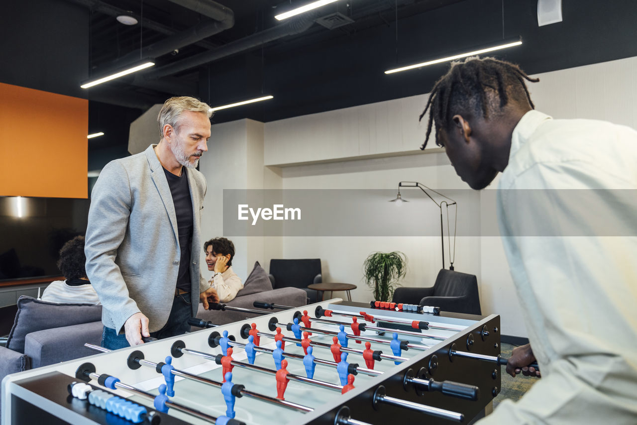 Businessmen playing foosball in office