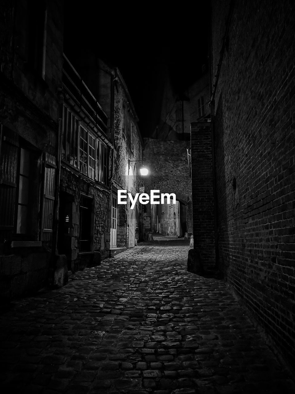 Empty alley amidst buildings at night