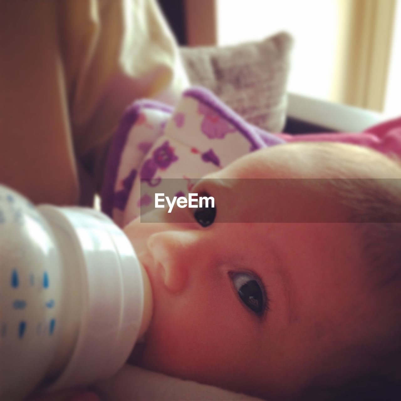 Close-up of mother feeding baby girl with milk bottle