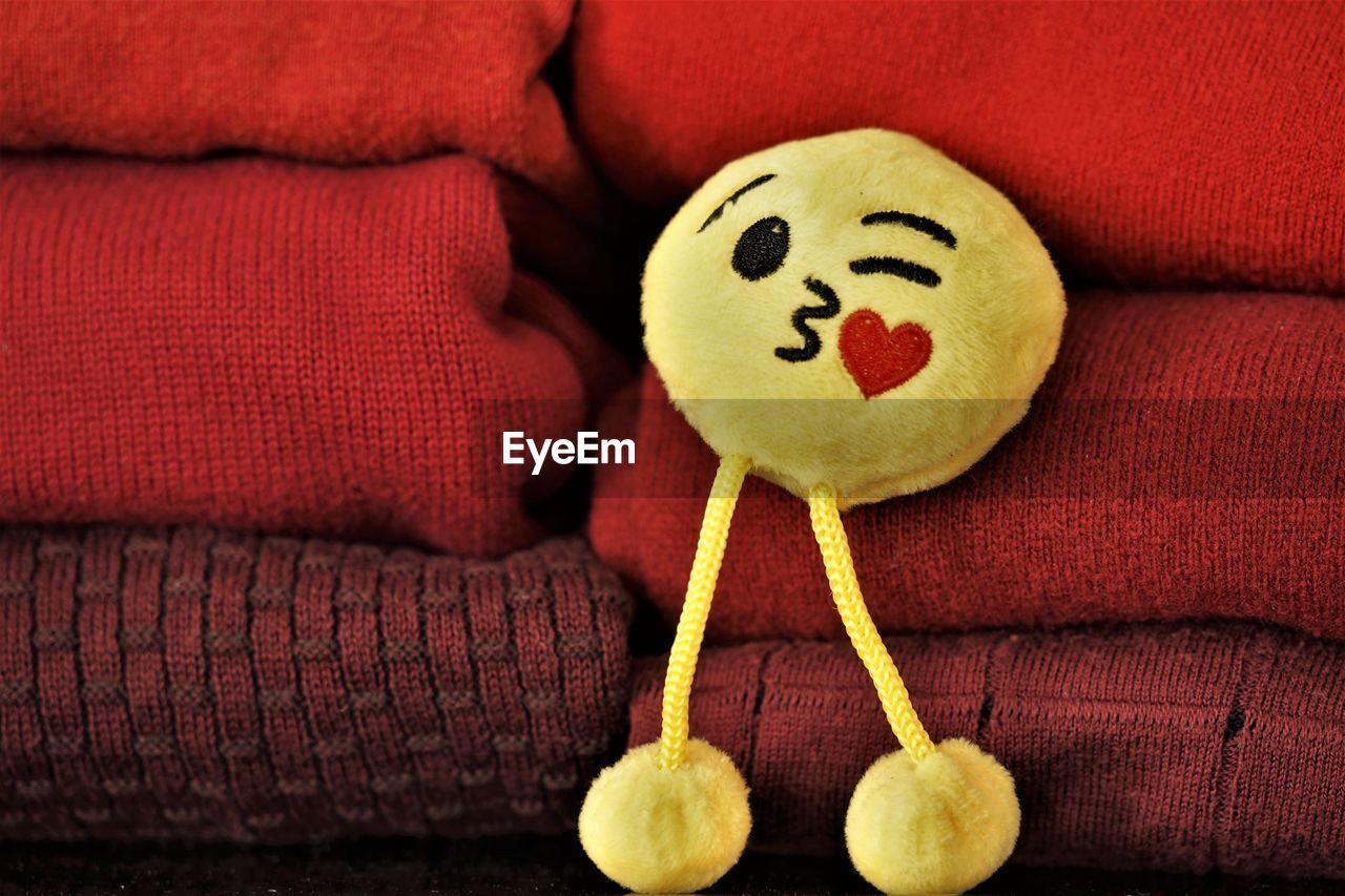 yellow, smiley, indoors, anthropomorphic smiley face, sofa, cartoon, no people, red, representation, textile, close-up, furniture, anthropomorphic, creativity, smiling, fun, toy, food and drink, still life, anthropomorphic face, food, emotion, stuffed toy, face, animal representation, craft