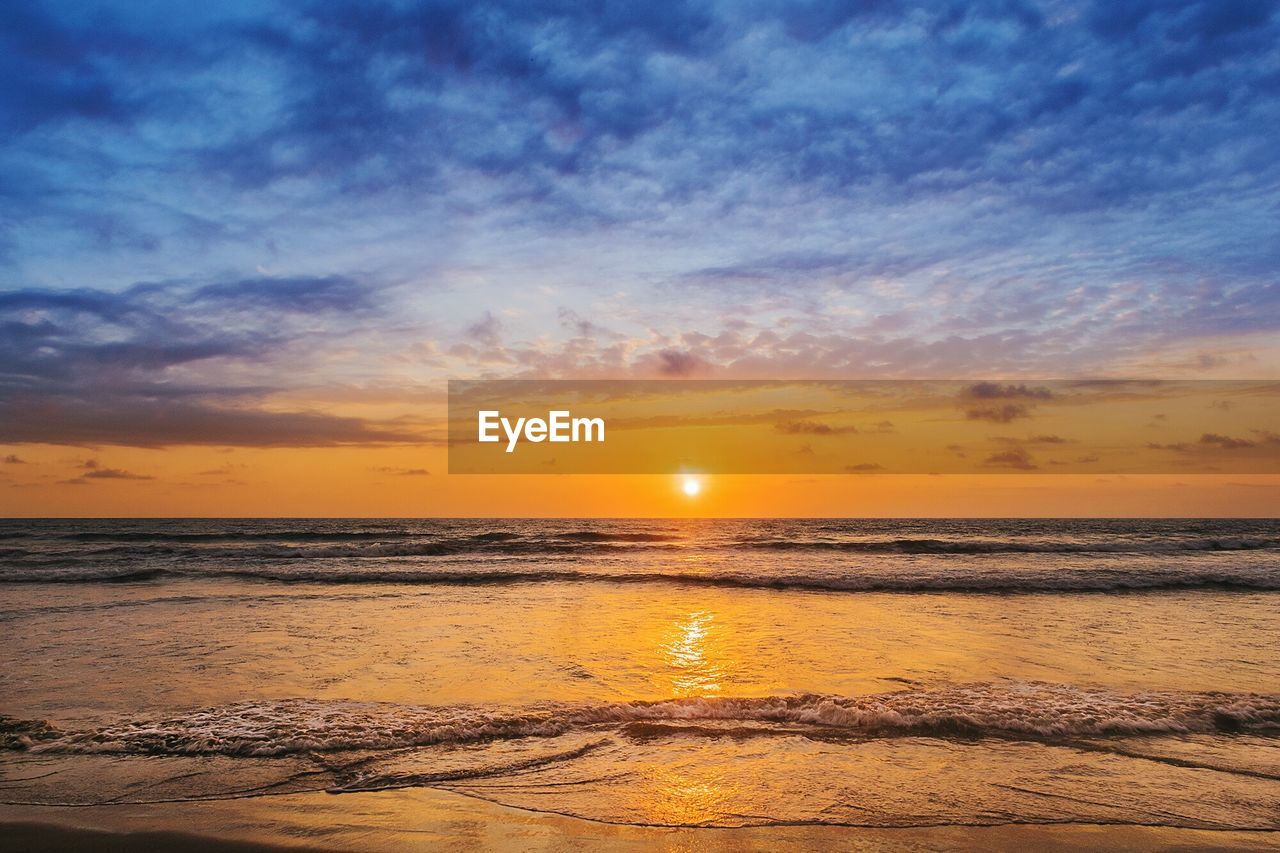 Scenic view of sea against dramatic sky during sunset