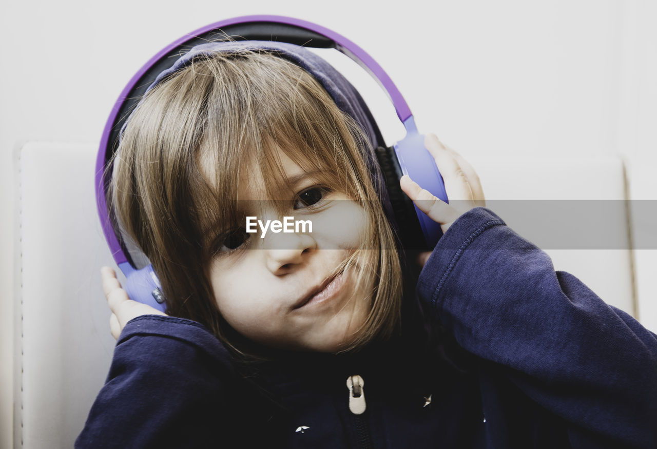 Close-up portrait of cute girl listening music through headphones