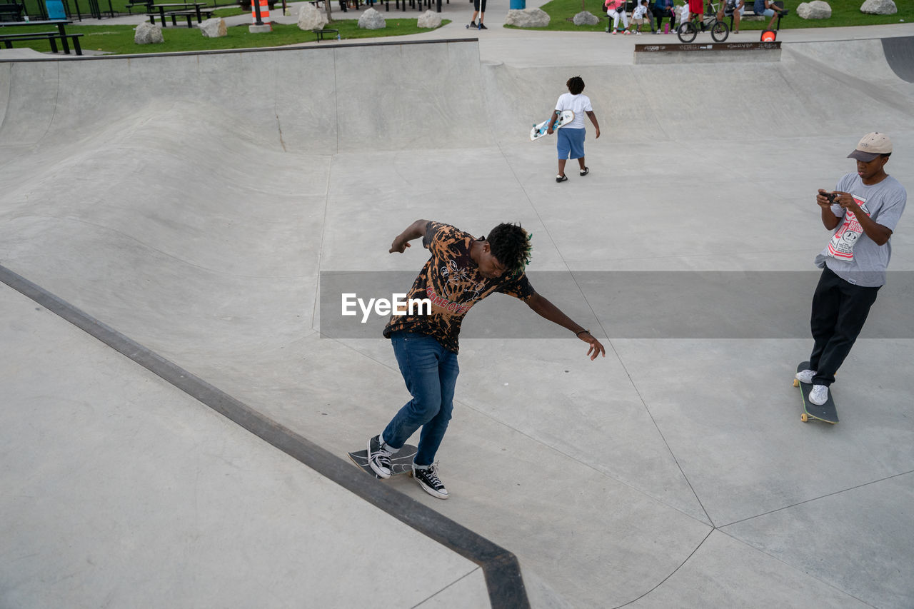 FULL LENGTH OF MOTHER WITH SKATEBOARD ON ROAD