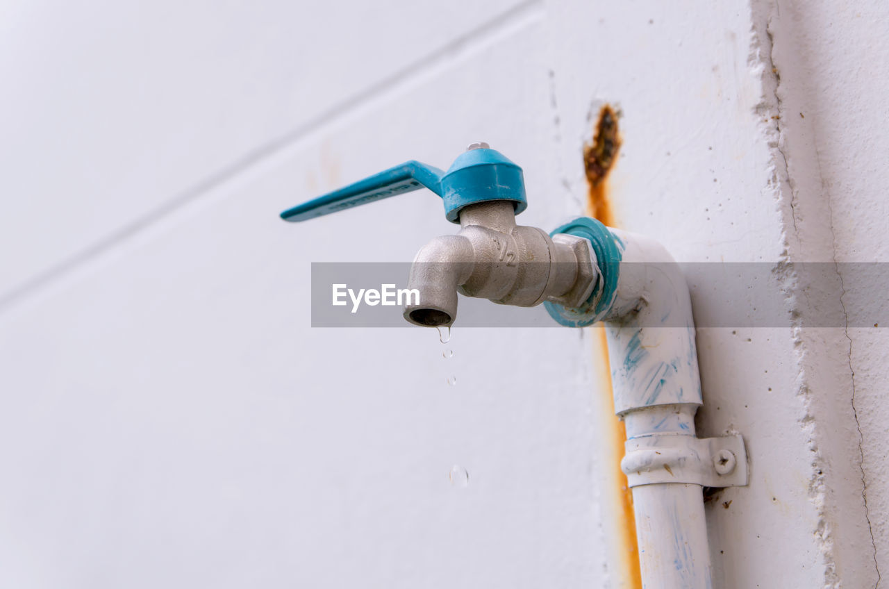 Close-up of faucet against white wall