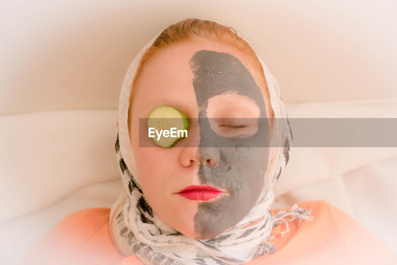 Directly above view of woman with mud pack and cucumber at spa