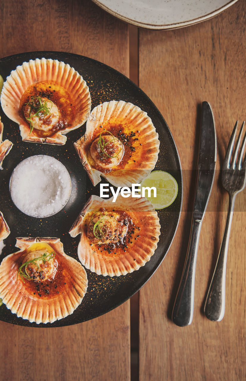 Scallops with flamed shells on a black plate. luxury restaurant food. seafood, selective focus.