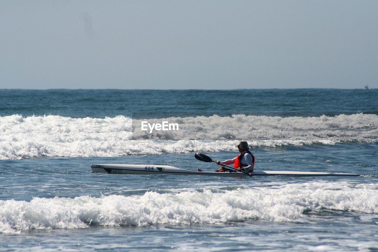 Man kayaking in sea against clear sky