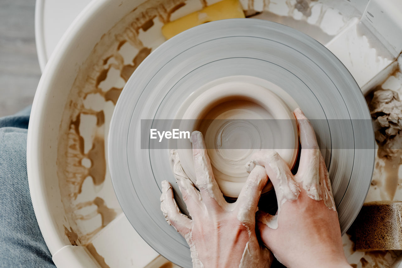 Female hands of potter forming clay product on potters wheel