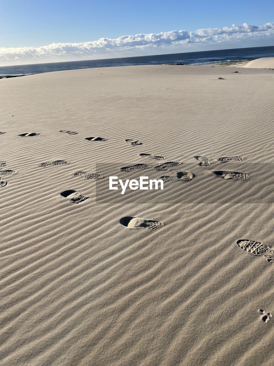 sand, land, beach, nature, day, beauty in nature, scenics - nature, sunlight, sand dune, tranquility, no people, natural environment, pattern, line, sky, water, landscape, desert, outdoors, sea, dune, high angle view, tranquil scene, wood, footprint, travel, wave pattern, environment, sunny, non-urban scene