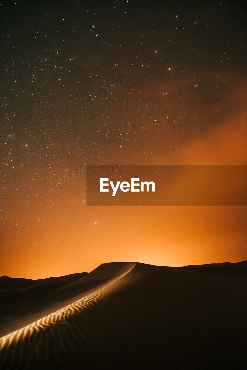 Scenic view of silhouette landscape against sky at night in the desert full of stars