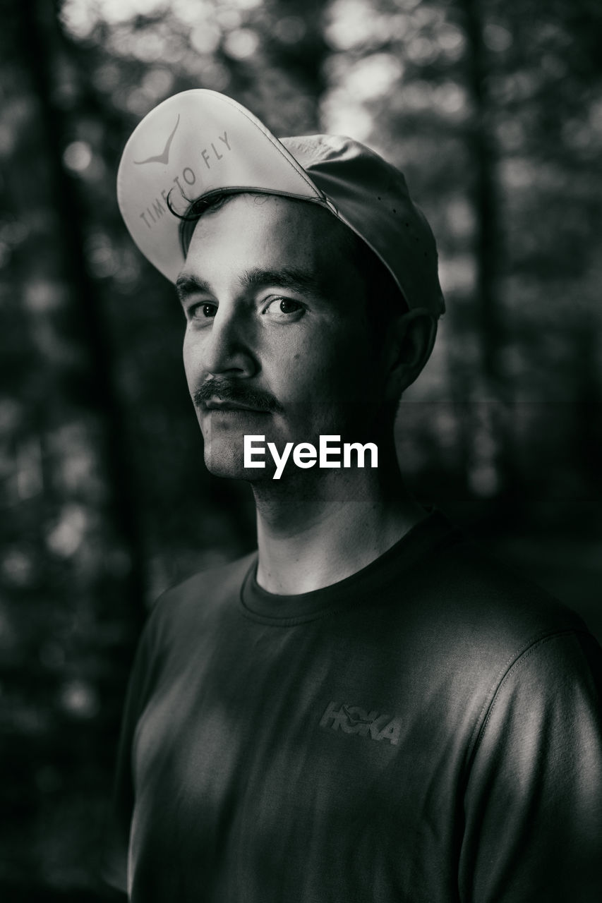 PORTRAIT OF YOUNG MAN STANDING AGAINST TREES