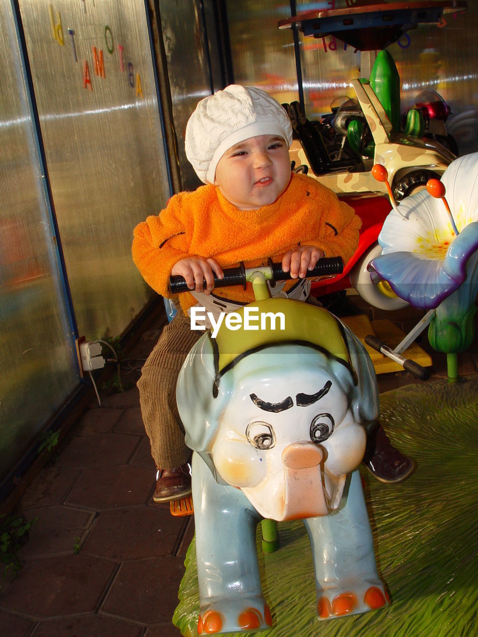 Baby boy sitting on carousel at amusement park