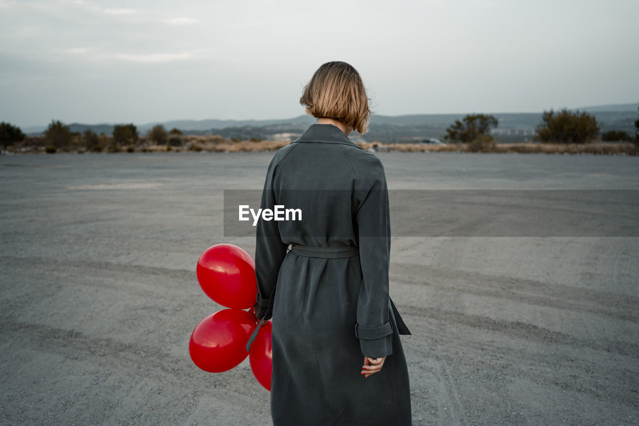 Mid adult woman holding balloon while standing at road