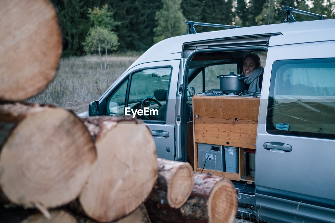 Woman in car by logs