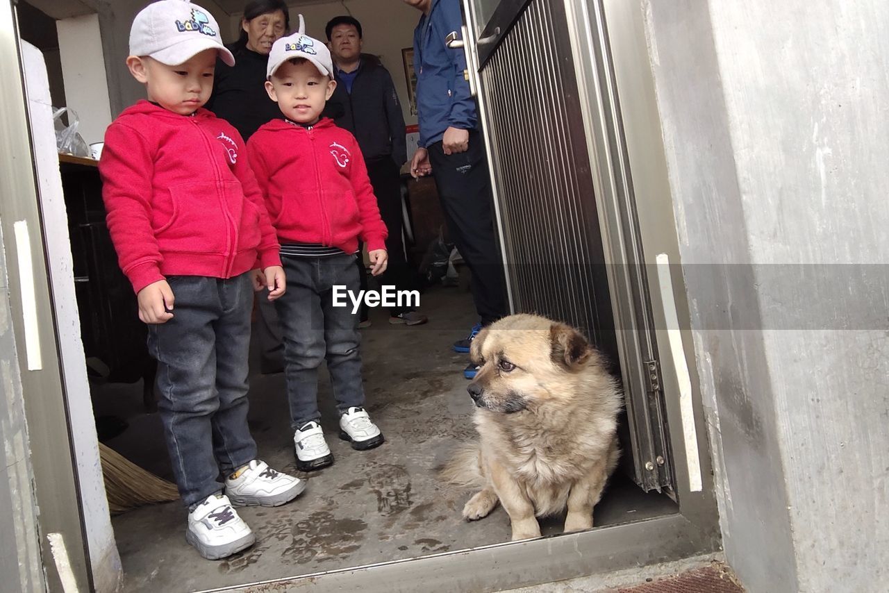 FULL LENGTH OF MEN STANDING WITH DOG AT HOME