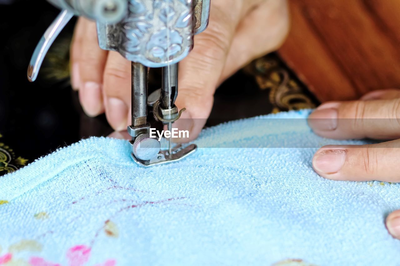 Cropped hand of tailor using sewing machine